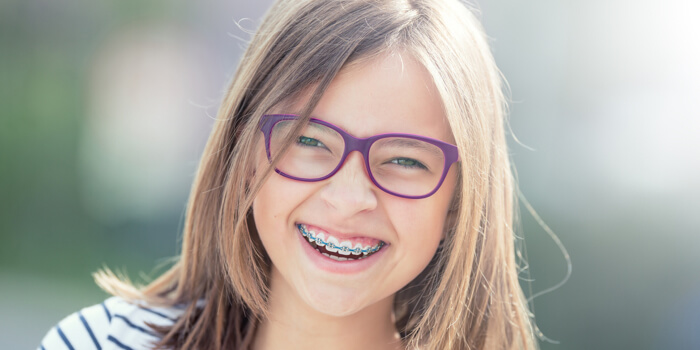 child with purple glasses happy with braces